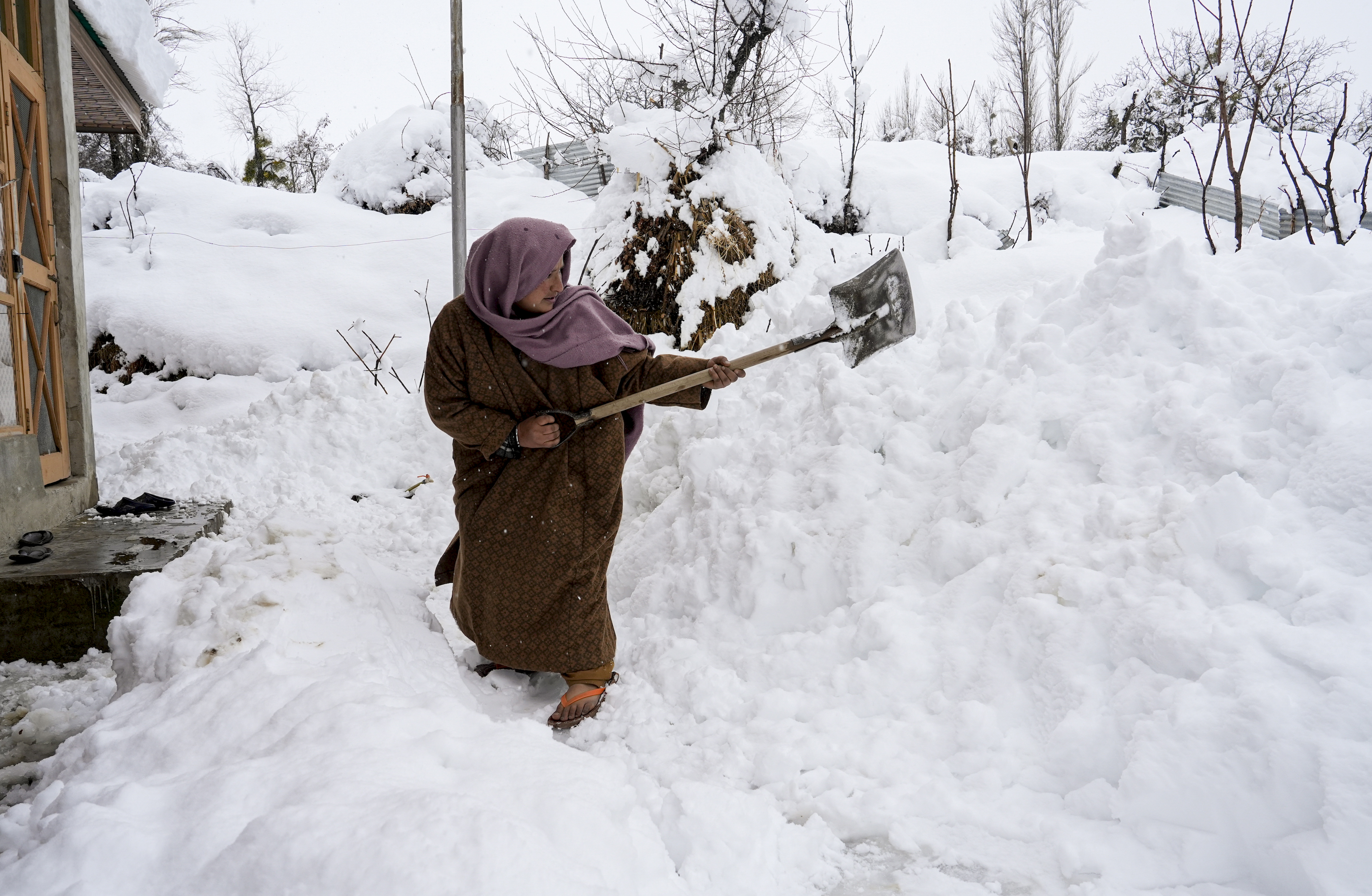 Budgam: A woman clears a snow-covered path outside her house during the seasonâs first snowfall, in Budgam, Jammu and Kashmir, Friday, Jan. 23, 2026. (PTI Photo/S Irfan)(PTI01_23_2026_000438B)